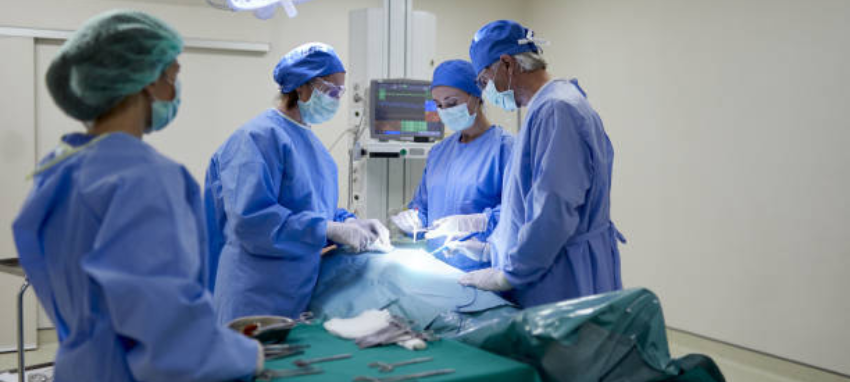 A patient is lying on an operating table and surgeons are performing surgery in an operating room.