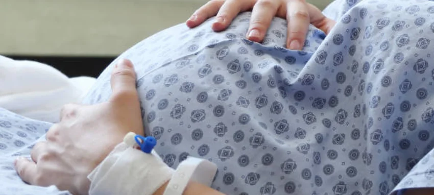 A pregnant woman is receiving support and care while resting in a hospital bed.