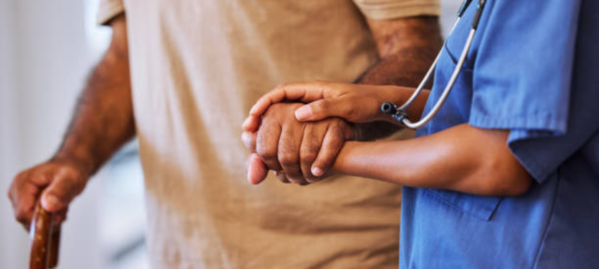 A compassionate nurse providing comfort & support by holding the hand of a patient in need of care
