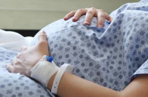 A pregnant woman lying in a hospital bed, receiving medical care and support during her pregnancy