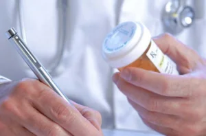 A doctor writing on paper with a pen, documenting medical information.