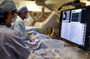 Two doctors in surgical gear analyzing a monitor displaying medical data.