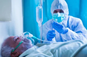 A man in a hospital bed wearing a mask and gloves, receiving medical care for snake bite